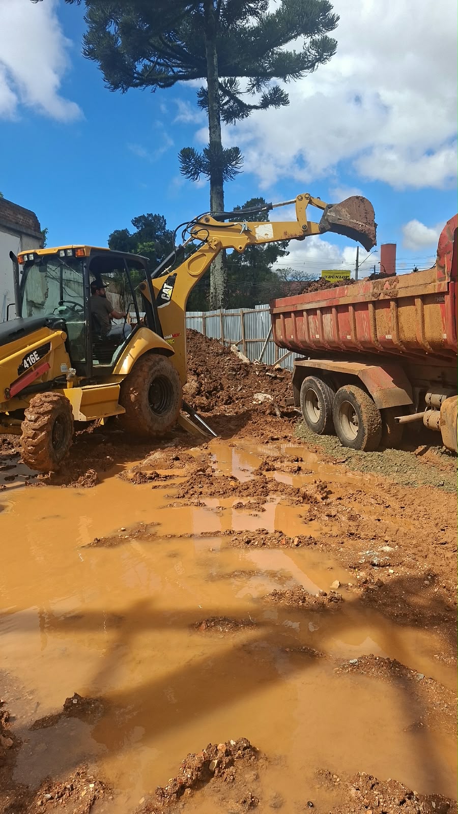 Retroescavadeira carregando terra em caminhão basculante